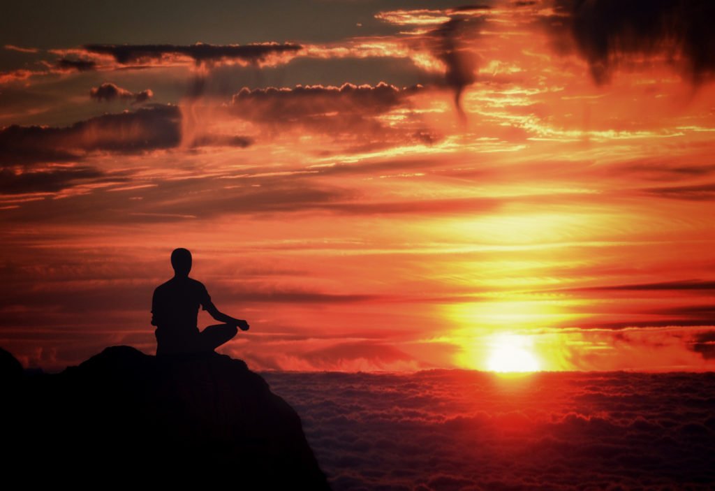 Person Meditating at Sunset Over the